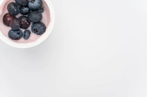 Высокоугольный Снимок Чашки Йогурта Свежими Ягодами Белой Поверхности — стоковое фото