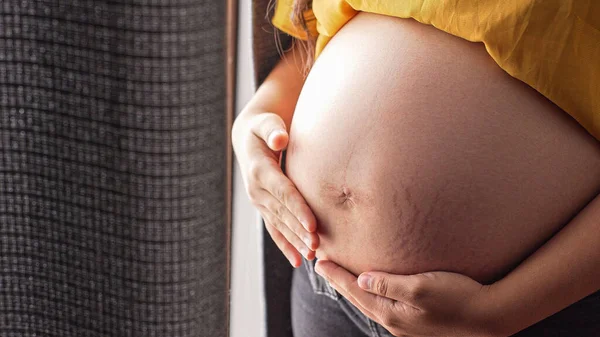 Närbild Gravid Kvinna Som Står Inomhus Och Håller Sin Mage — Stockfoto