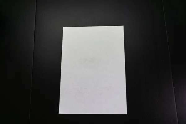 Een Blanco Papier Een Zwarte Achtergrond — Stockfoto