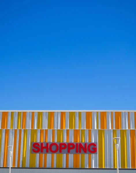 青い空と太陽の下で建物の上に赤い ショッピング の看板の垂直ショット — ストック写真