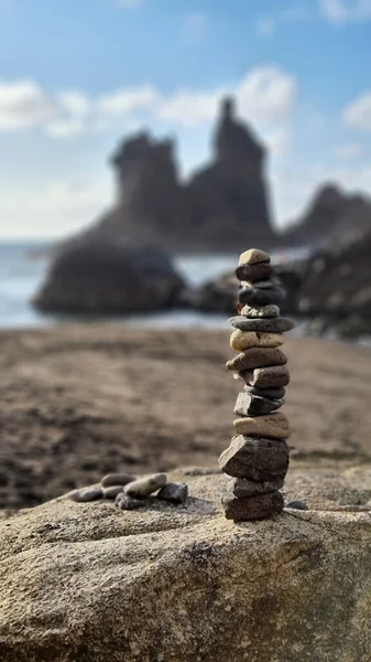 背景がぼんやりとしたビーチで 互いの上に積み上げられた小さな岩の垂直ショット — ストック写真