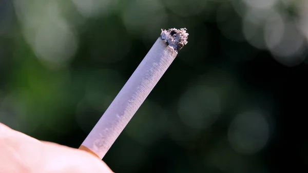 Foco Seletivo Uma Pessoa Segurando Cigarro Queimado Contra Fundo Embaçado — Fotografia de Stock