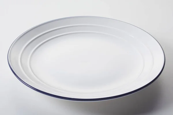 Ένα Λευκό Κεραμικό Πιάτο Ραβδώσεις Μπλε Χείλος Λευκό Φόντο — Φωτογραφία Αρχείου