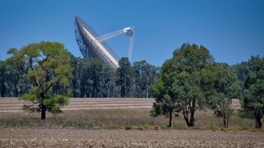 The CSIRO Parkes radio telescope pointing to the sky from across the paddocks in NSW Australia clipart