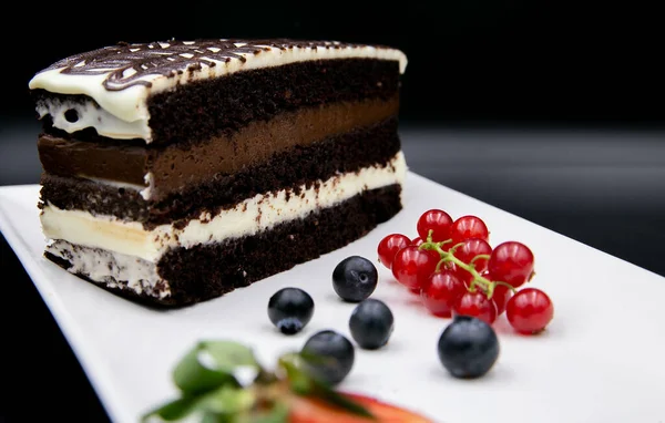 Ein Schokoladenkuchenstück Auf Einem Weißen Teller Mit Beeren Auf Schwarzem — Stockfoto