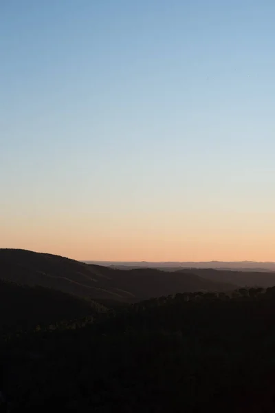 Een Verticaal Shot Van Lichtblauwe Lucht Zonsopgang Boven Heuvels Bedekt — Stockfoto