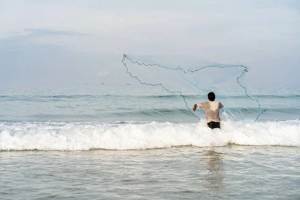一只雄性带着渔网在沙滩上与融化的海景和天际线合影 — 图库照片