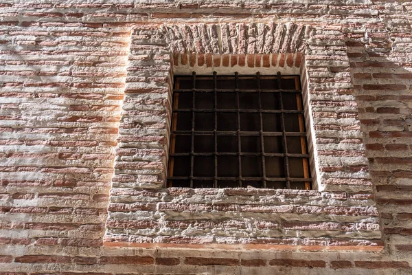 带铁栅栏的小正方形窗户的旧砖楼的低角 — 图库照片