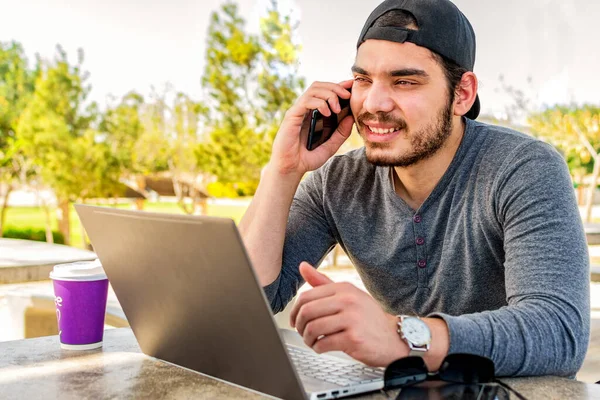 Młody Szczęśliwy Przedsiębiorca Pracujący Online Rozmawiający Klientem Przez Telefon Parku — Zdjęcie stockowe