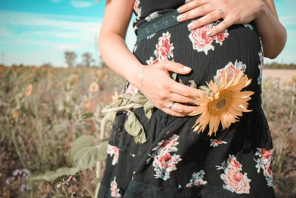 ひまわり畑に花のドレスを着た妊婦 — ストック写真