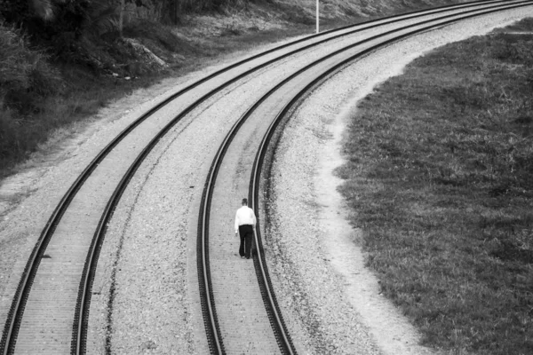 鉄道を歩いている一人の男のグレースケール — ストック写真