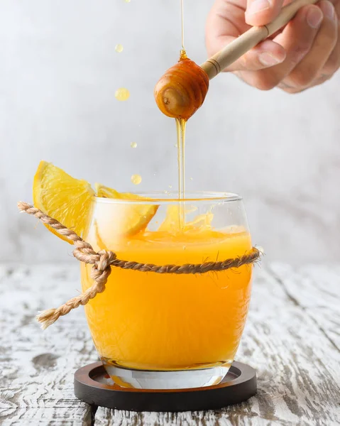 Вертикальный Снимок Яркого Апельсинового Напитка Мужской Рукой Обливает Медом — стоковое фото
