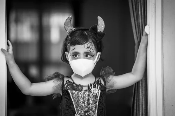 一个身穿万圣节服装 化着卫生面具的东南亚女孩的灰白照片 — 图库照片