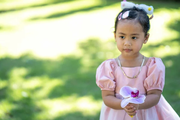 Uma Menina Asiática Adorável Que Prende Uma Flor Orchid Que — Fotografia de Stock