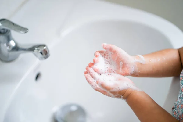 A high angle shot of a little girl washing hands with soap