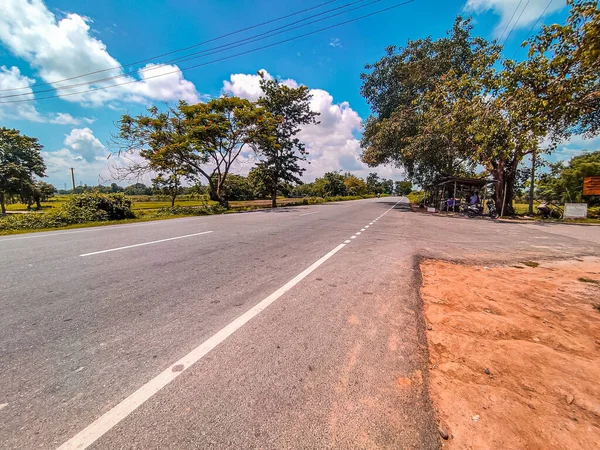 Belo Tiro Uma Estrada Cercada Por Campos Árvores Dia Ensolarado — Fotografia de Stock