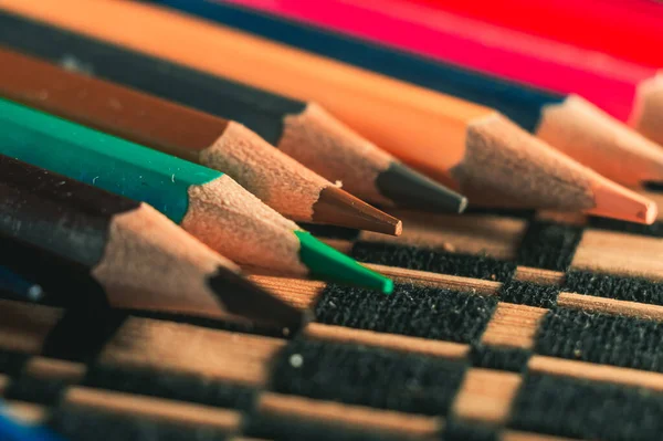 Ένα Κοντινό Πλάνο Από Χρωματιστά Ακονισμένα Μολύβια Ένα Πολύχρωμο Τραπεζομάντιλο — Φωτογραφία Αρχείου