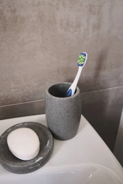 A vertical shot of a toothbrush and the soap on a sink in the bathroom