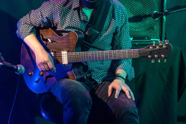 在音乐会上穿着衬衫在舞台上弹奏吉他的男人的特写 — 图库照片