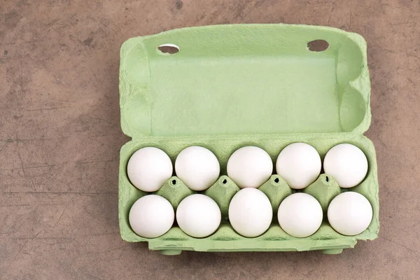 A top-view of fresh eggs in a green egg carton