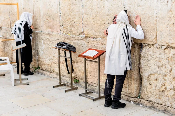 Orthodox Jewish man with tefillin and tallit, sitting alone and