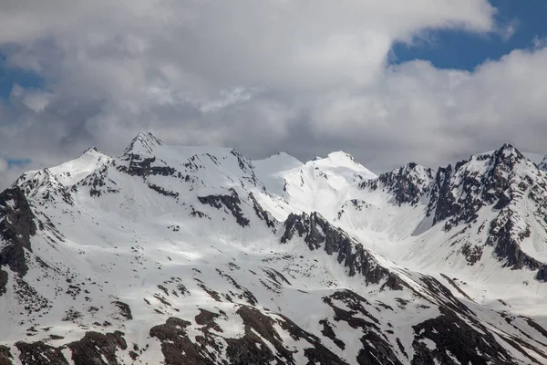 多云的天空笼罩着阿尔卑斯山高处的雪景 — 图库照片