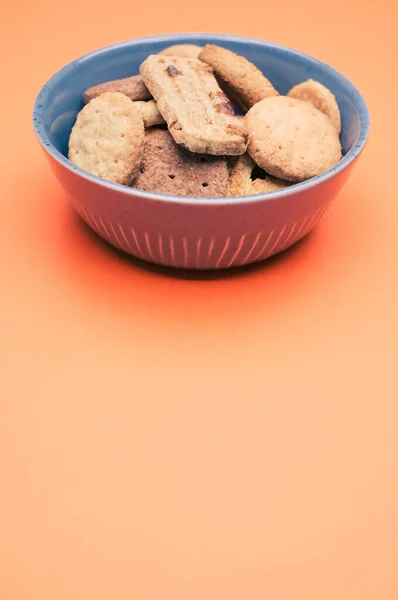 Tiro Vertical Galletas Orgánicas Tazón Azul Sobre Una Superficie Naranja — Foto de Stock