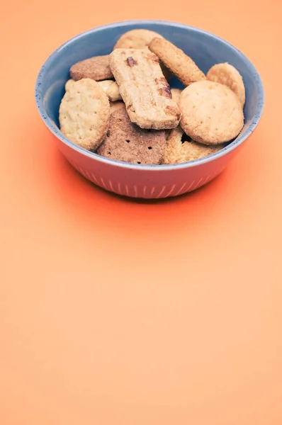 Tiro Vertical Galletas Orgánicas Tazón Azul Sobre Una Superficie Naranja — Foto de Stock