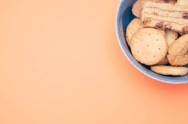 Tiro Vertical Galletas Orgánicas Tazón Azul Sobre Una Superficie Naranja —  Fotos de Stock