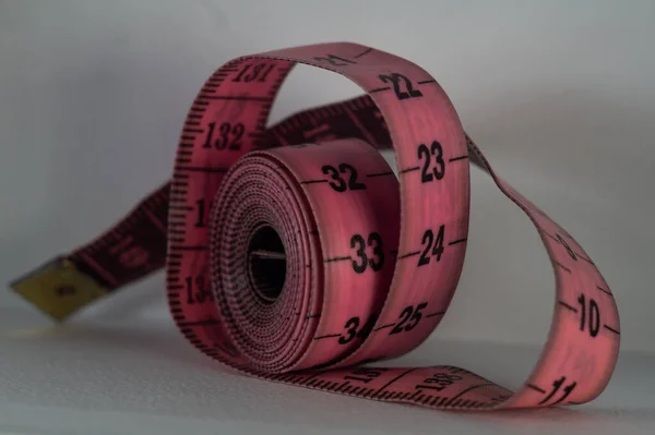 白い表面にピンクのテープメジャーのロールのクローズアップショット — ストック写真