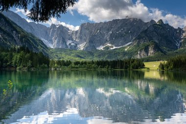 This small lake in Italy, surrounded by impressive mountains, is very close to the border with Austria clipart