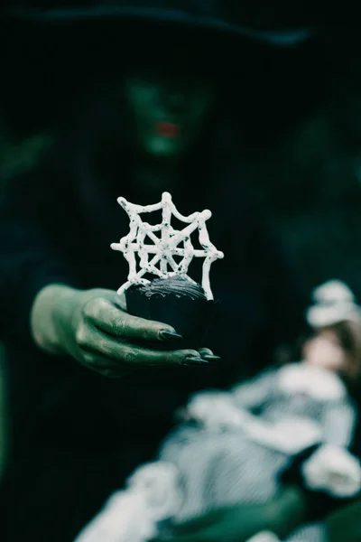 Вертикальный Снимок Зеленой Руки Ведьмы Кексом Украшенным Паутиной Тематика Хэллоуина — стоковое фото