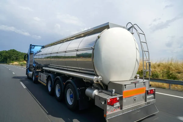 a closeup shot of rear tanker truck on highway road by dense forest at daylight