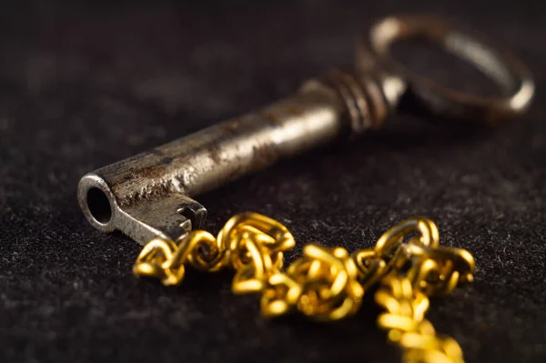 Schlüsselanhänger Und Goldkette Auf Dunkler Oberfläche — Stockfoto