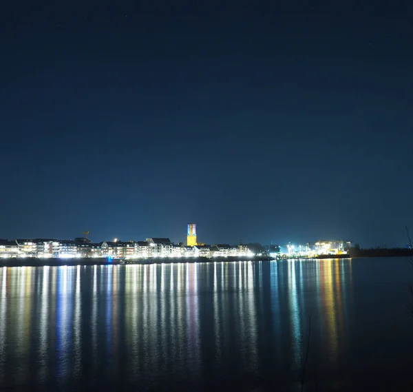 一个海滨小镇的夜景 明亮的灯光在晴朗的天空下反射在海面上 — 图库照片