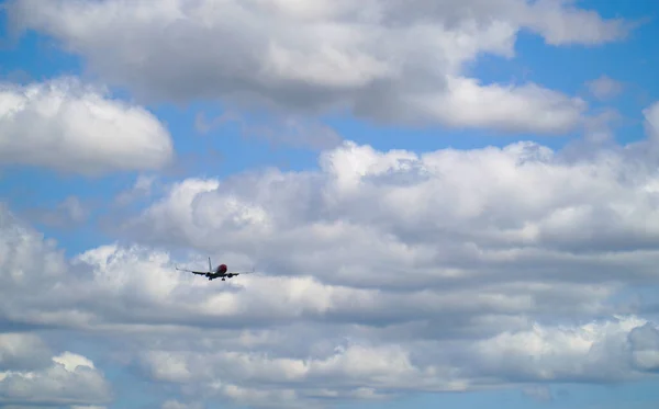 在蓝云的天空下 一架飞机飞到远处的摄像机旁边拍到的照片 — 图库照片
