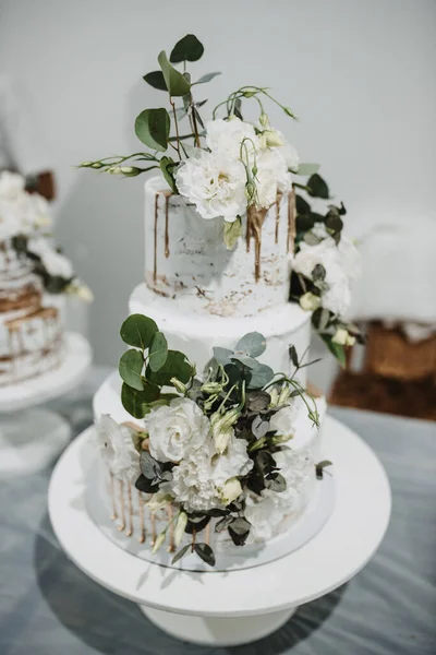 白いバラと葉で飾られた大きなウェディングケーキの垂直ショット — ストック写真