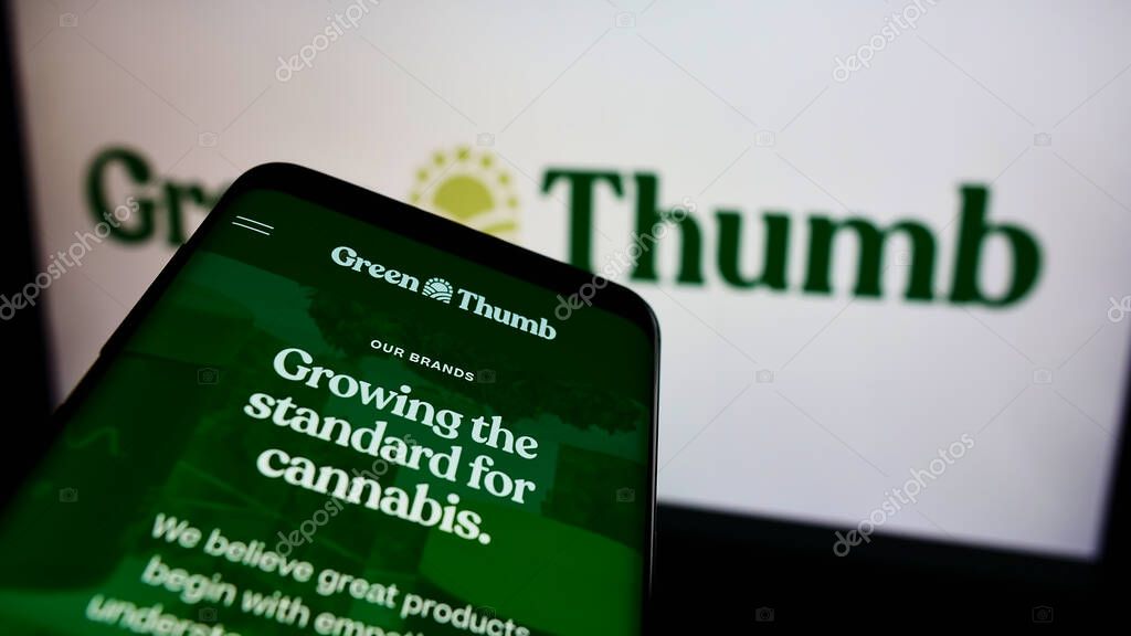 STUTTGART, GERMANY - Aug 14, 2021: Mobile phone with webpage of American cannabis company Green Thumb Industries Inc. on screen in front of logo. Focus on top-left of phone display.