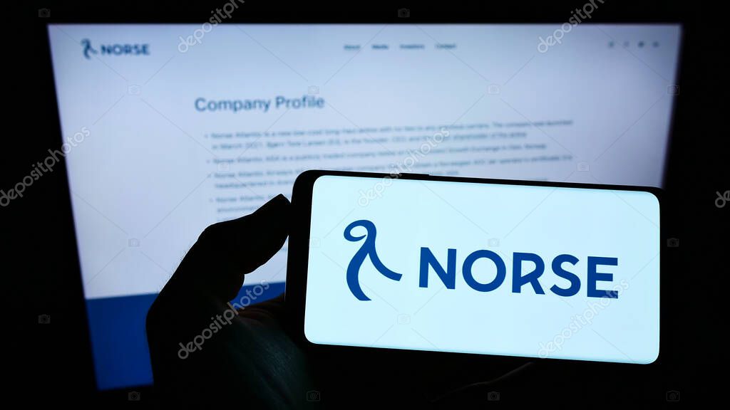 STUTTGART, GERMANY - Aug 15, 2021: Person holding smartphone with logo of Norwegian airline Norse Atlantic Airways on screen in front of website. Focus on phone display.