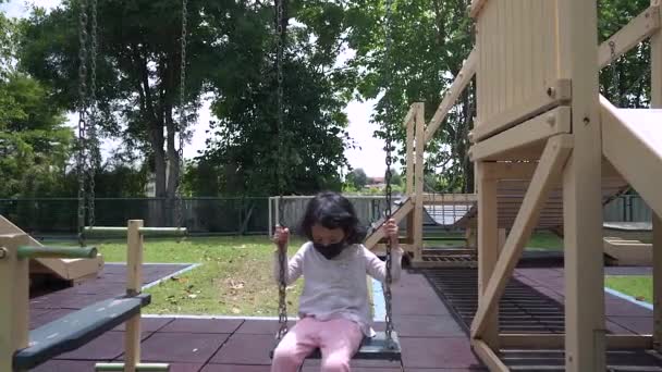 Cute Girl Facial Mask Swinging Playground — стоковое видео