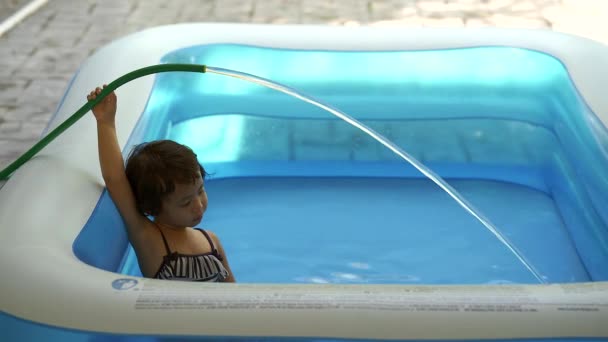 Cute Asian Girl Holding Water Hose White Sitting Inflatable Pool — стокове відео