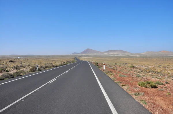 Long straight road through barren landscape of volcanic balearic island Lanzarote, Spain