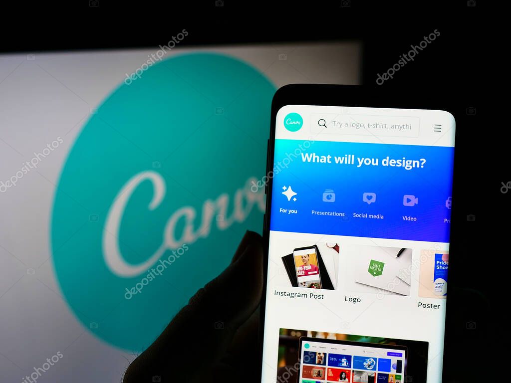 STUTTGART, GERMANY - Aug 14, 2021: Person holding cellphone with webpage of Australian graphic design company Canva on screen in front of logo. Focus on center of phone display.