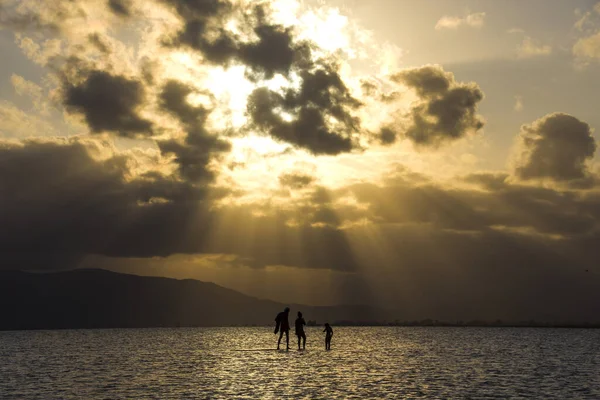 Σιλουέτες Των Ανθρώπων Στην Επιφάνεια Του Νερού Ένα Όμορφο Ηλιοβασίλεμα — Φωτογραφία Αρχείου