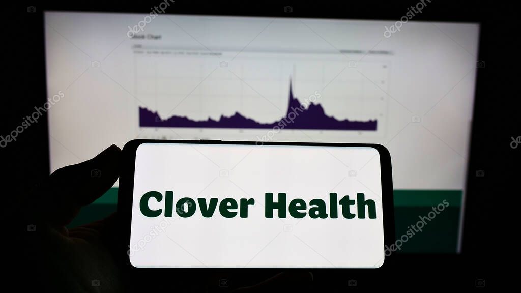 STUTTGART, GERMANY - Aug 16, 2021: Person holding mobile phone with logo of Clover Health Investments Corp. on screen in front of web page. Focus on phone display.