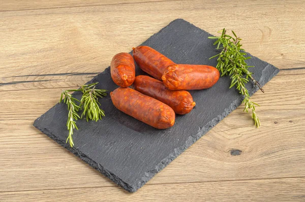 Smoked Pork Sausages Rosemary Leaves Gray Textured Board Wooden Table — Stock Photo, Image