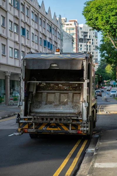 A rear view of a garbage truck running in the urban road