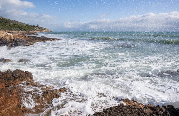 一道巨大美丽的海浪拍到了岩石海岸 背景是蓝天的特写镜头 — 图库照片