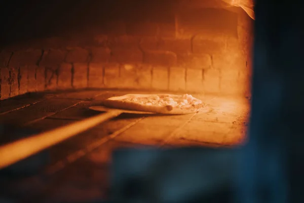 大きな火のついた石のオーブンで焼くピザのクローズアップショット — ストック写真