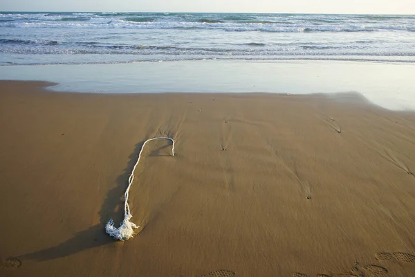 砂の上に転がり落ちる泡の波を持つ海岸のクローズアップショット — ストック写真
